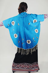 blue wool poncho with white embroidered flowers and white fringe on hem vintage 