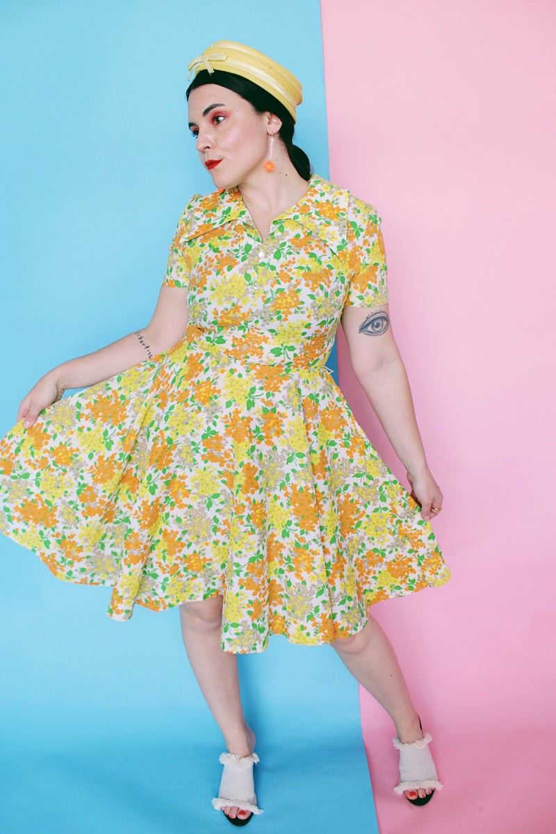 Women's vintage 1960's short sleeve polyester material mini length dress with all over green, orange, and yellow floral print. 