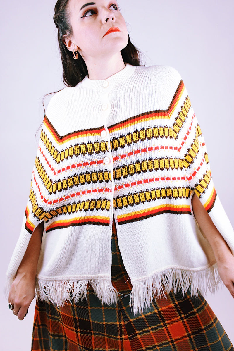 white vintage women's 1960's acrylic knit poncho with striped pattern and fringed hem