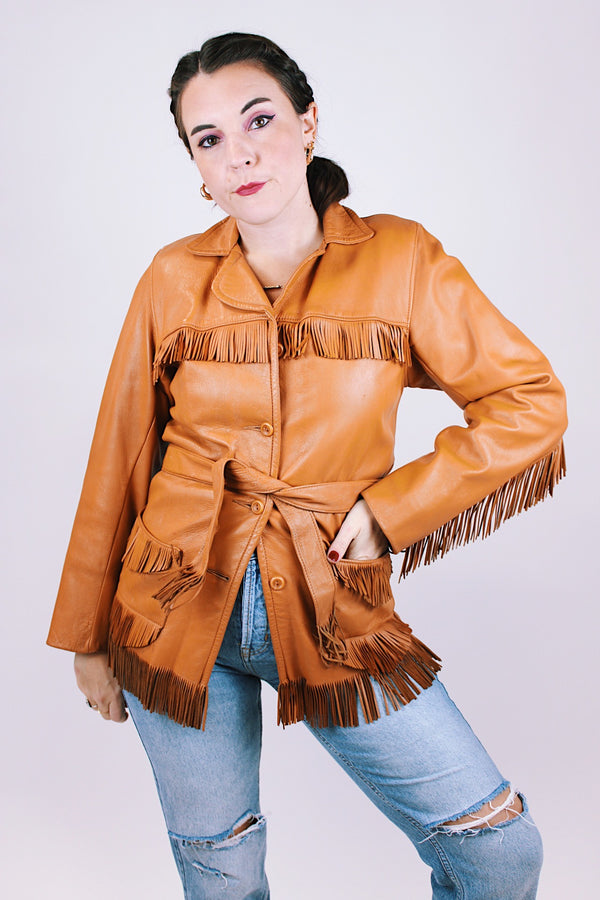 women's vintage leather jacket in camel collar with fringe trim detail, a tie waist, and buttons up the front