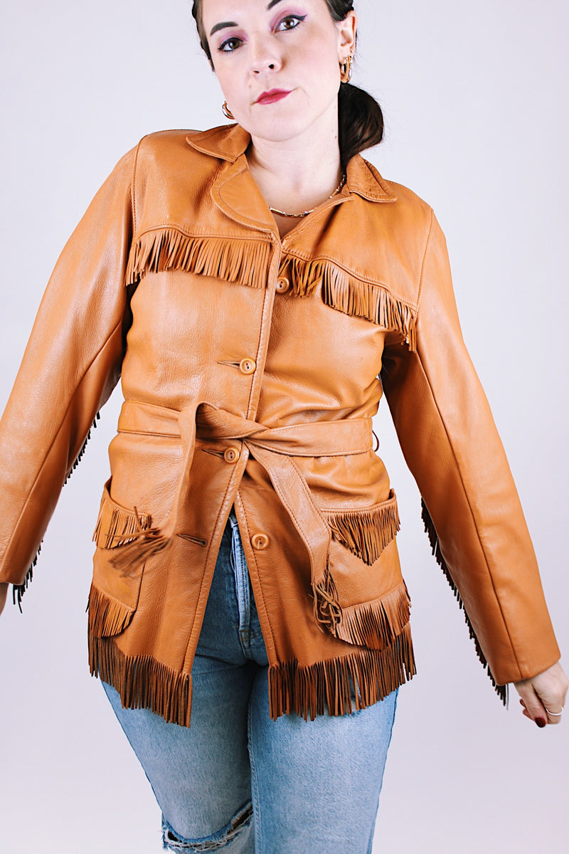 women's vintage leather jacket in camel collar with fringe trim detail, a tie waist, and buttons up the front